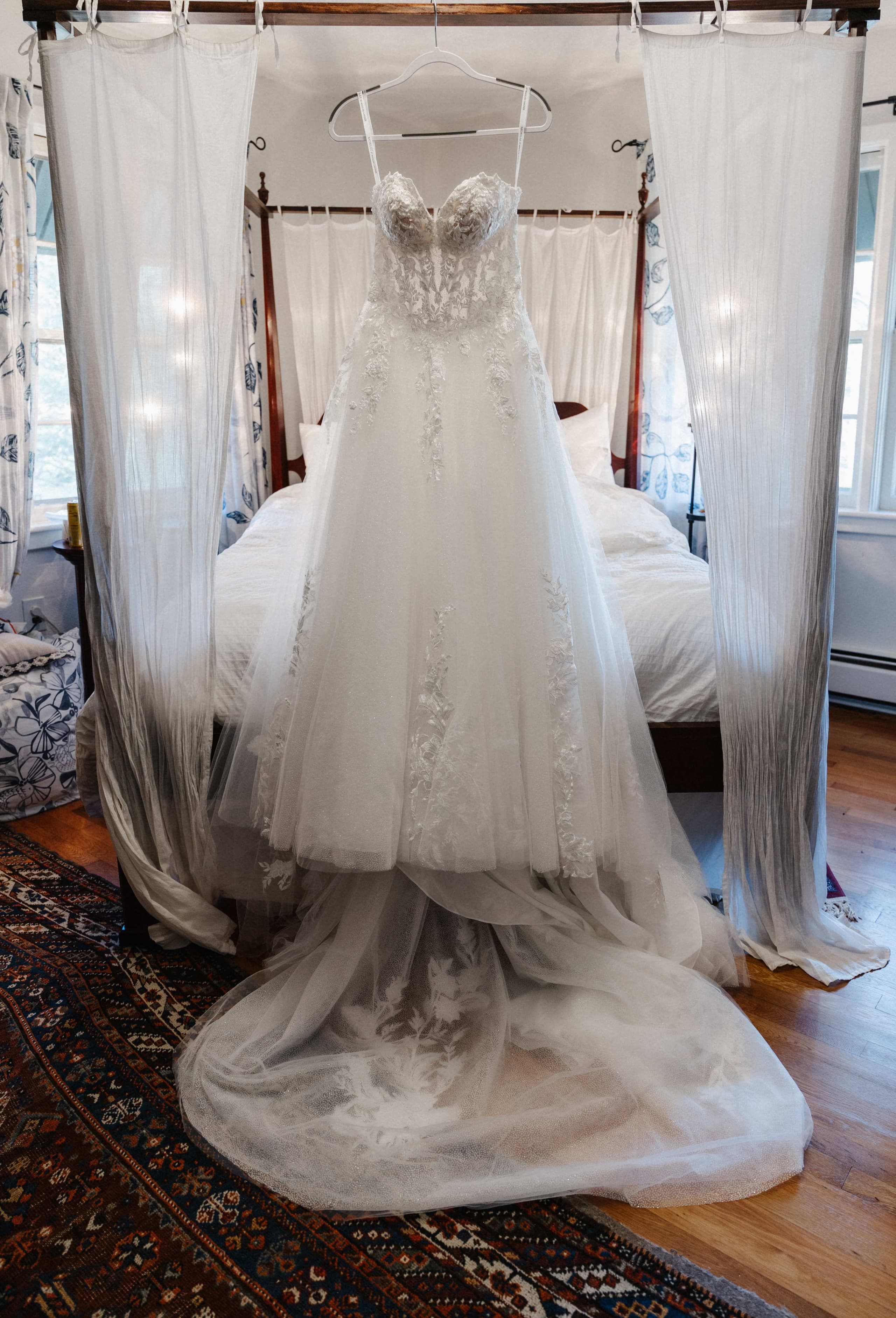 Lace and tulle wedding dress hanging on canopy bed