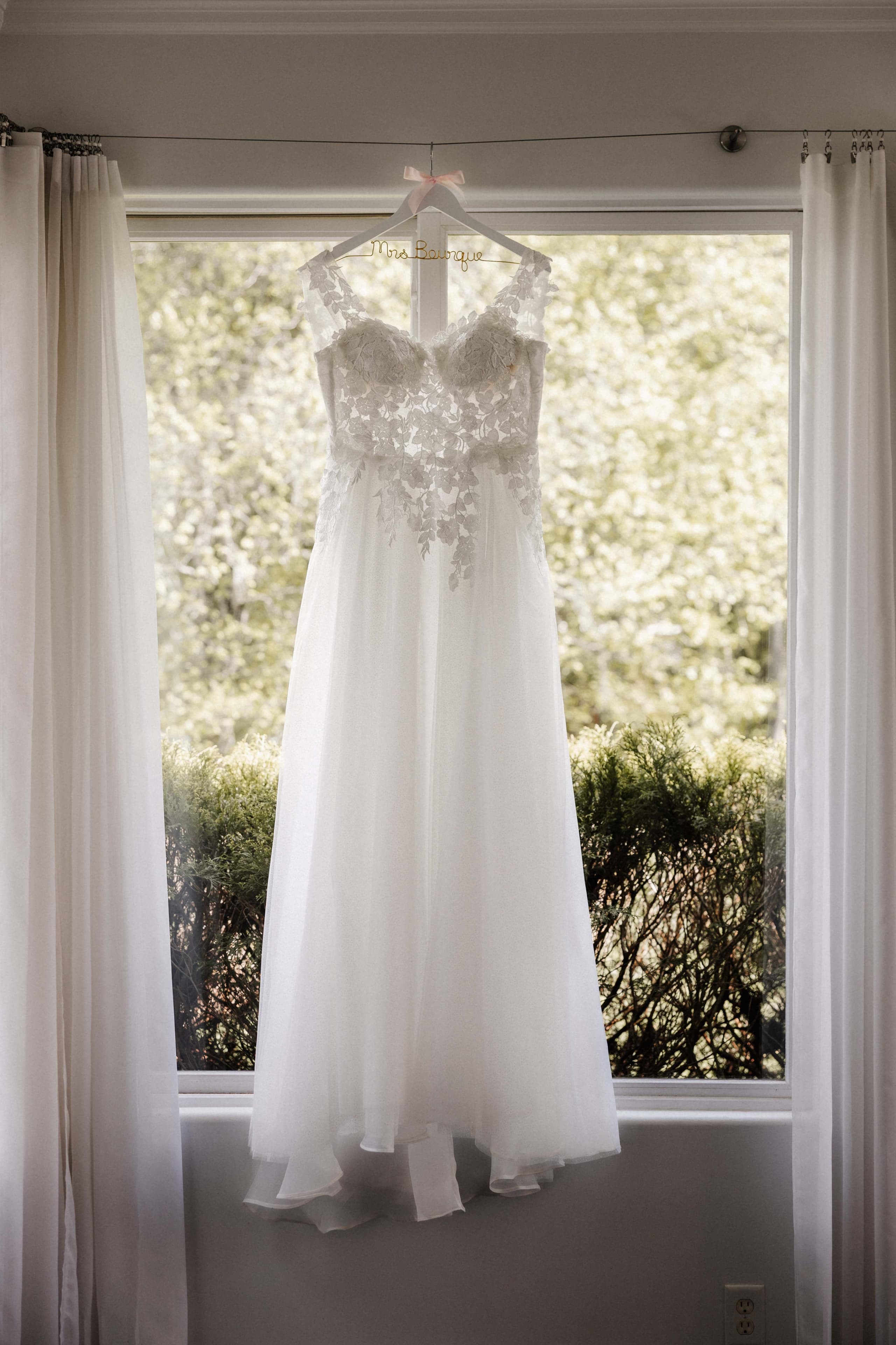 Wedding dress hanging in window with custom Mrs. name hanger