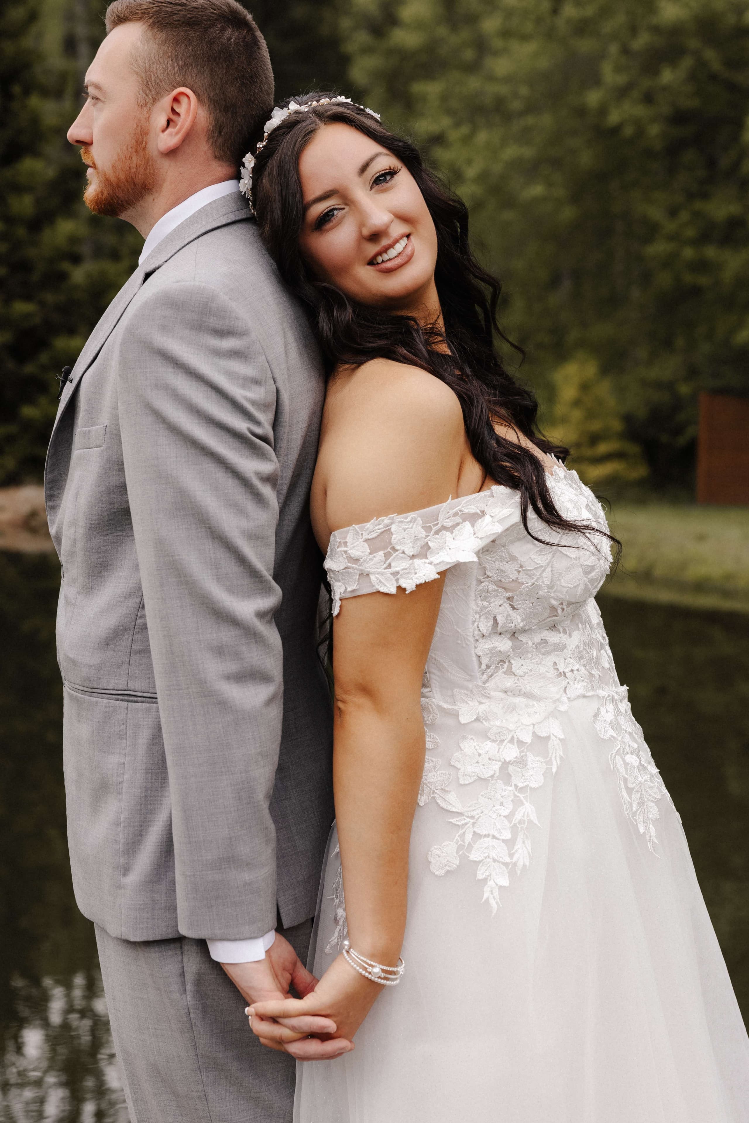 Bride smiling at camera during first look leaning on groom's back