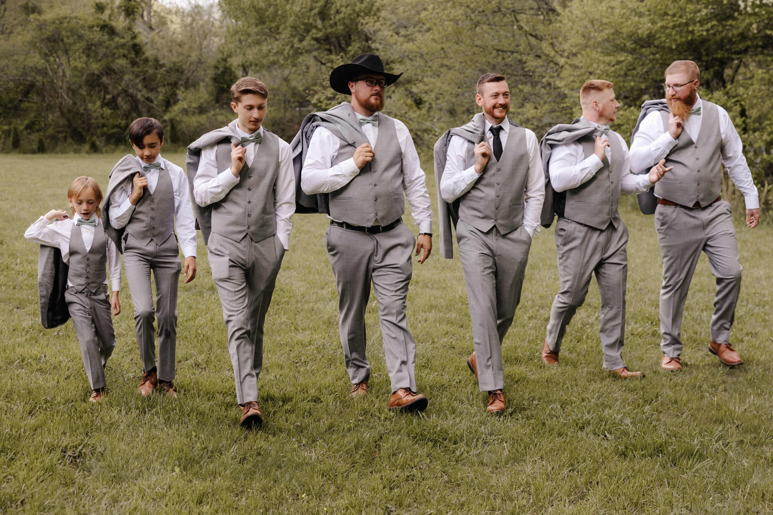 Groomsmen walking with jackets over shoulders in gray suits