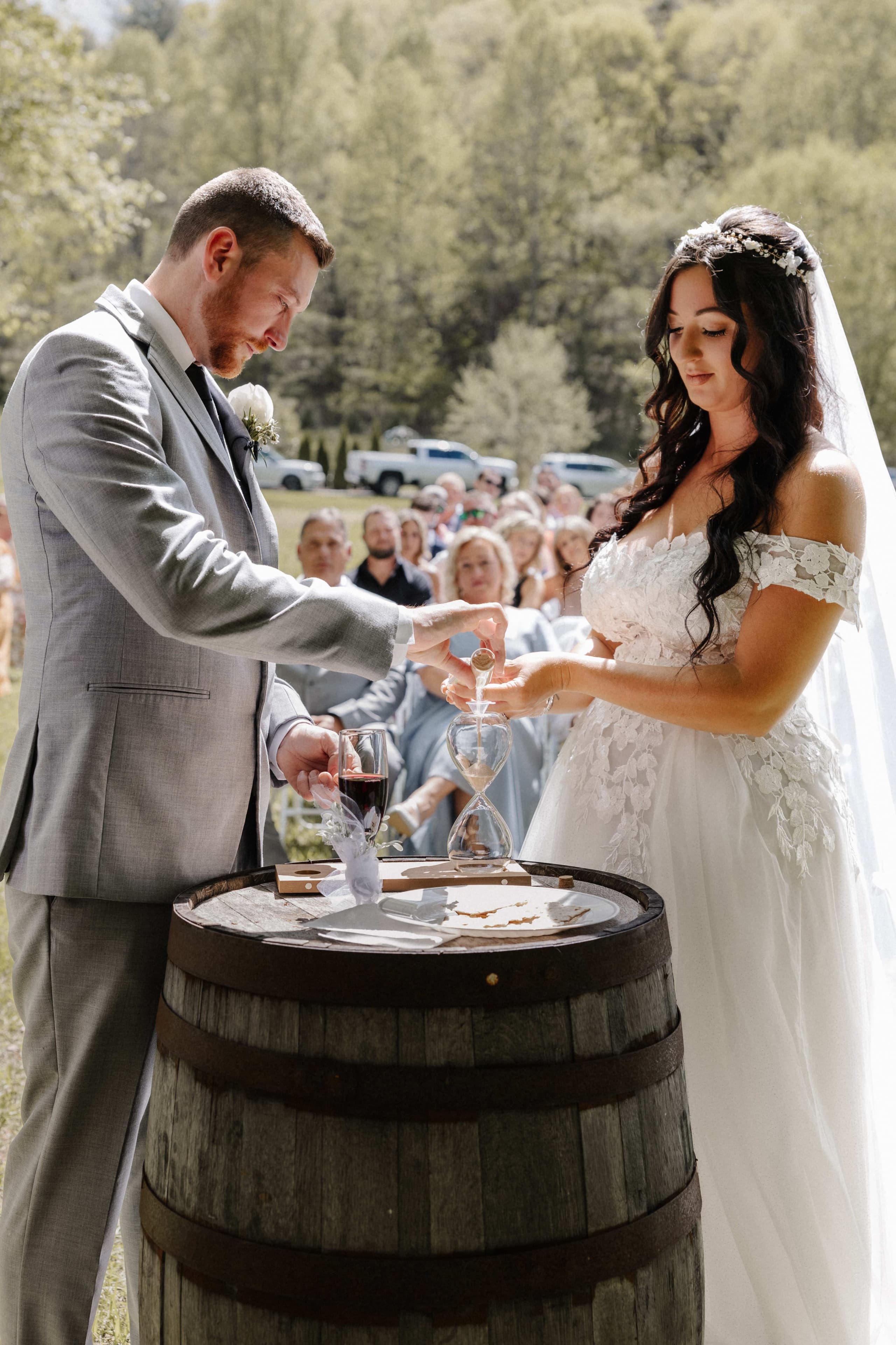 Unity sand ceremony at wine barrel during outdoor ceremony