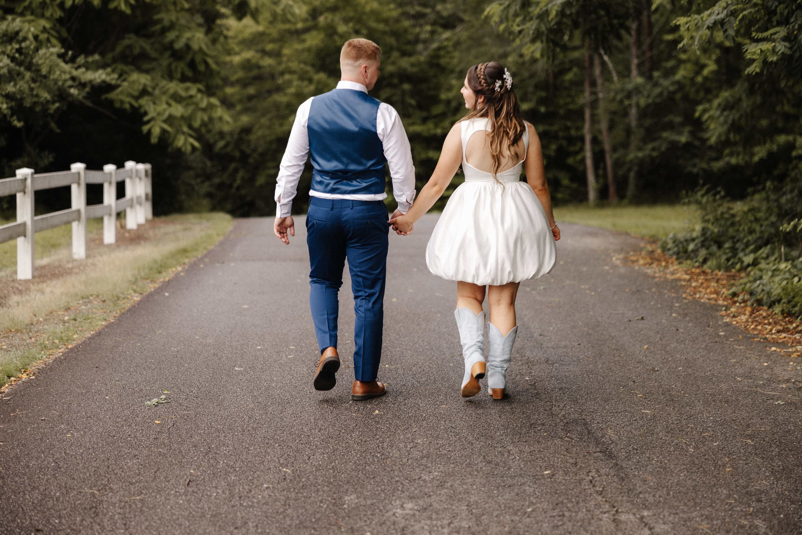 Couple walking away holding hands with bride in blue cowboy boots