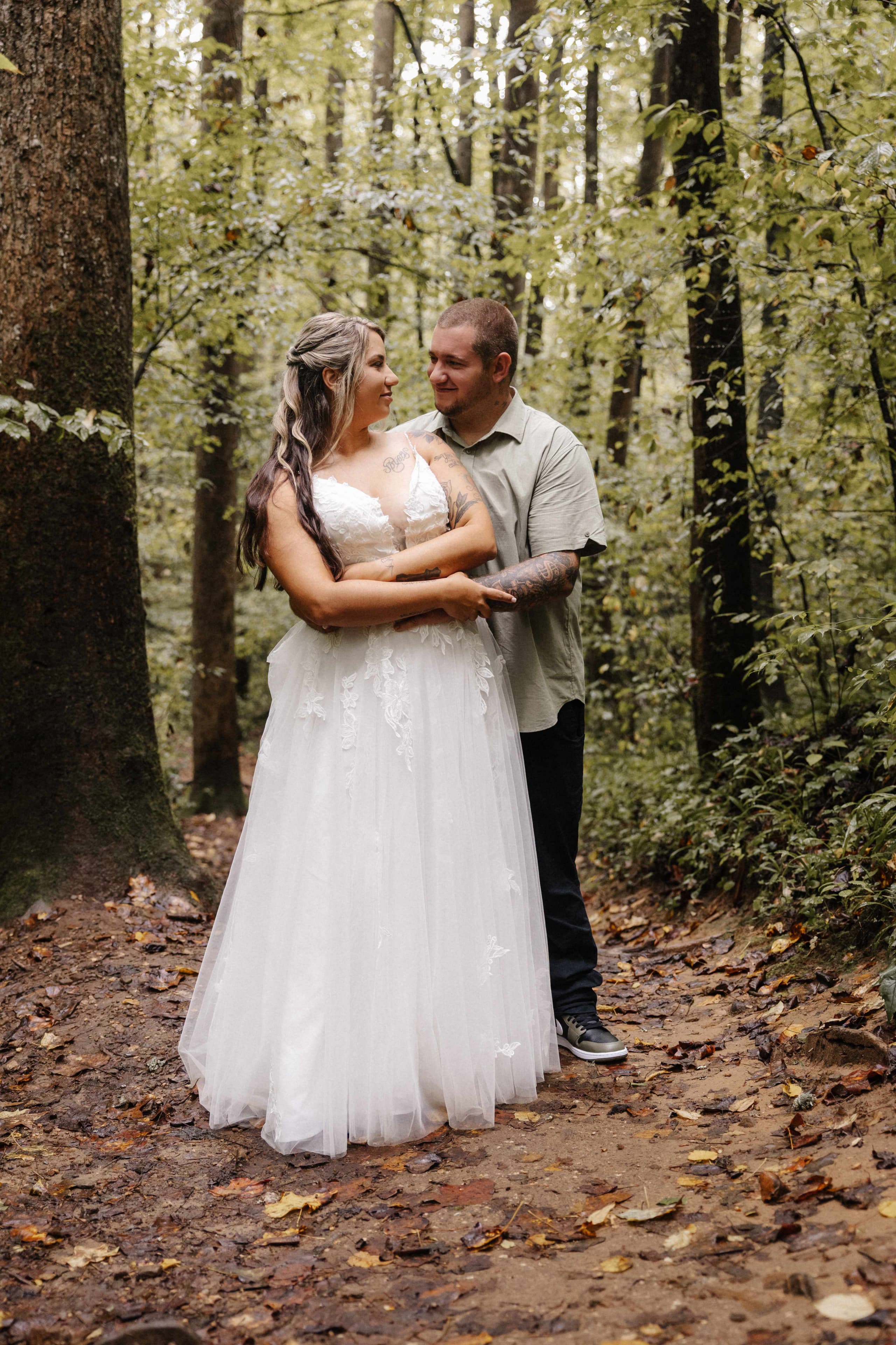 Couple embrace on forest path looking at each other