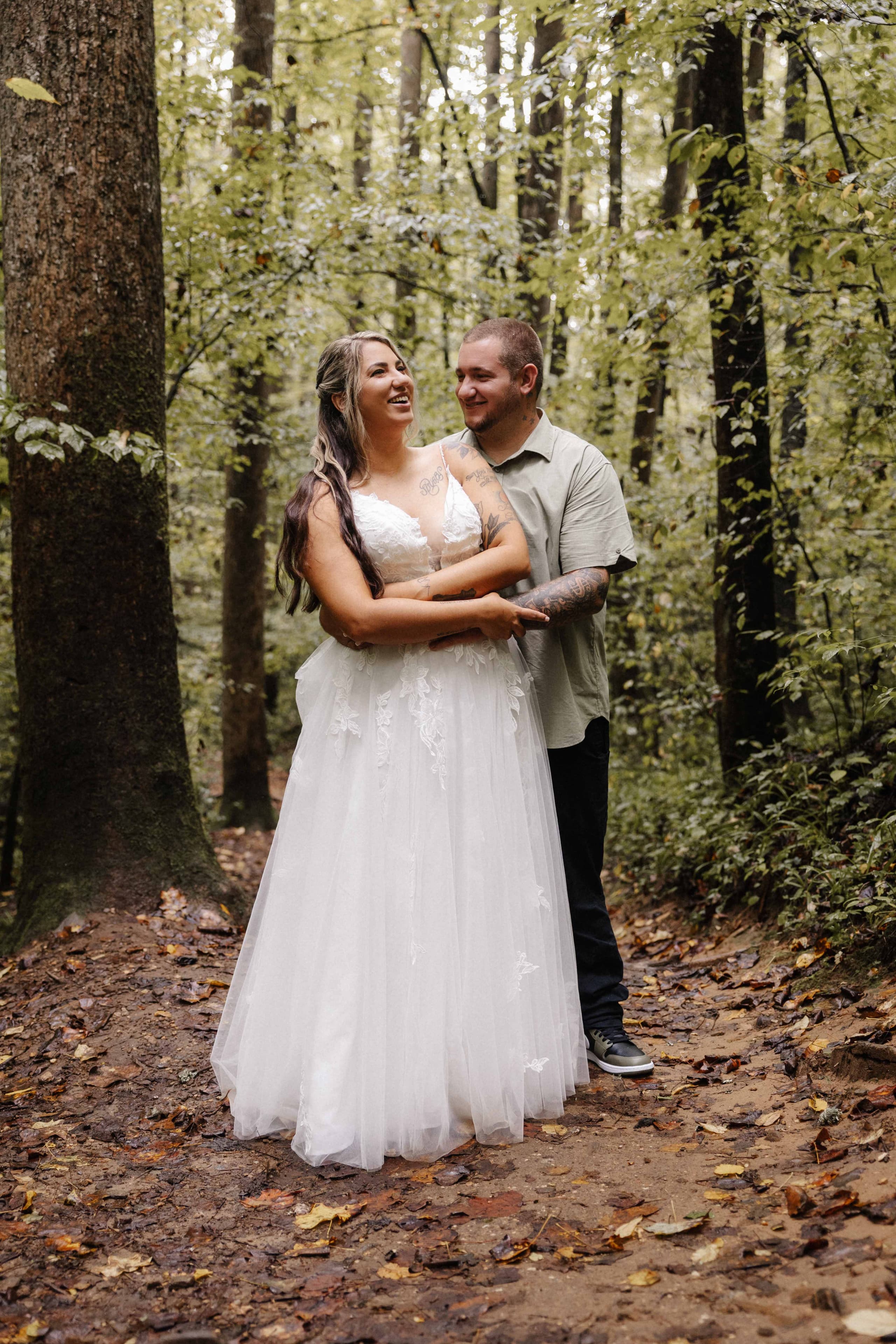 Couple laughing together on forest path with fall leaves