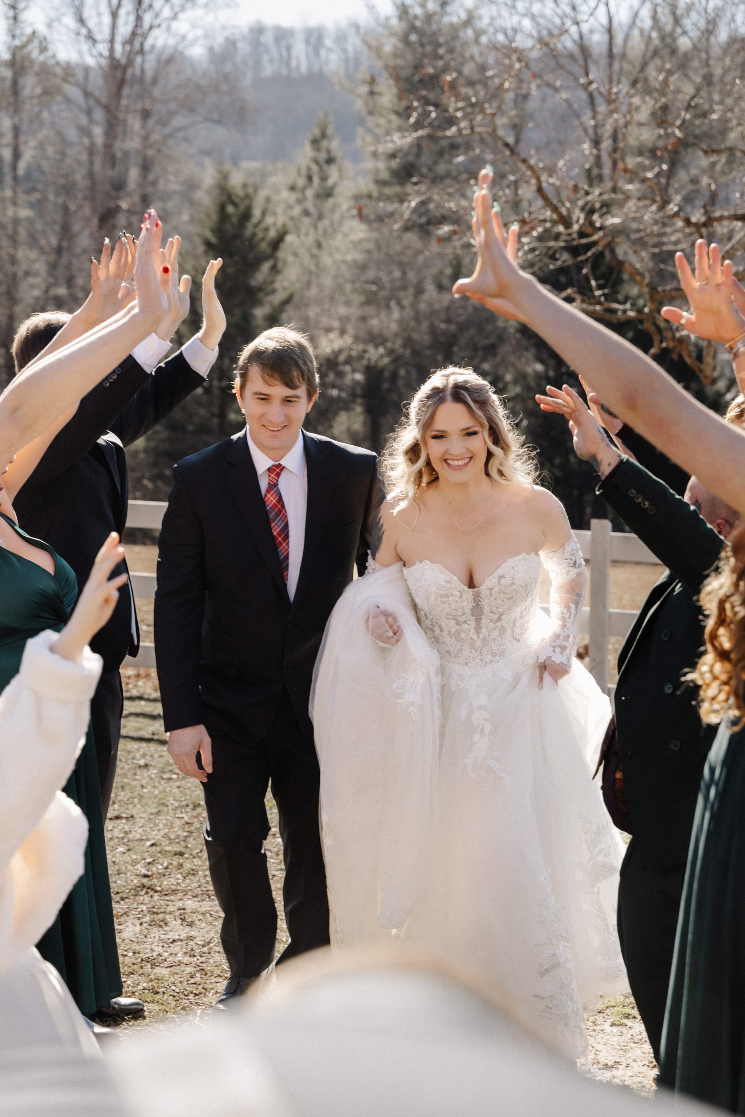Wedding party forming hand tunnel for couple walking through