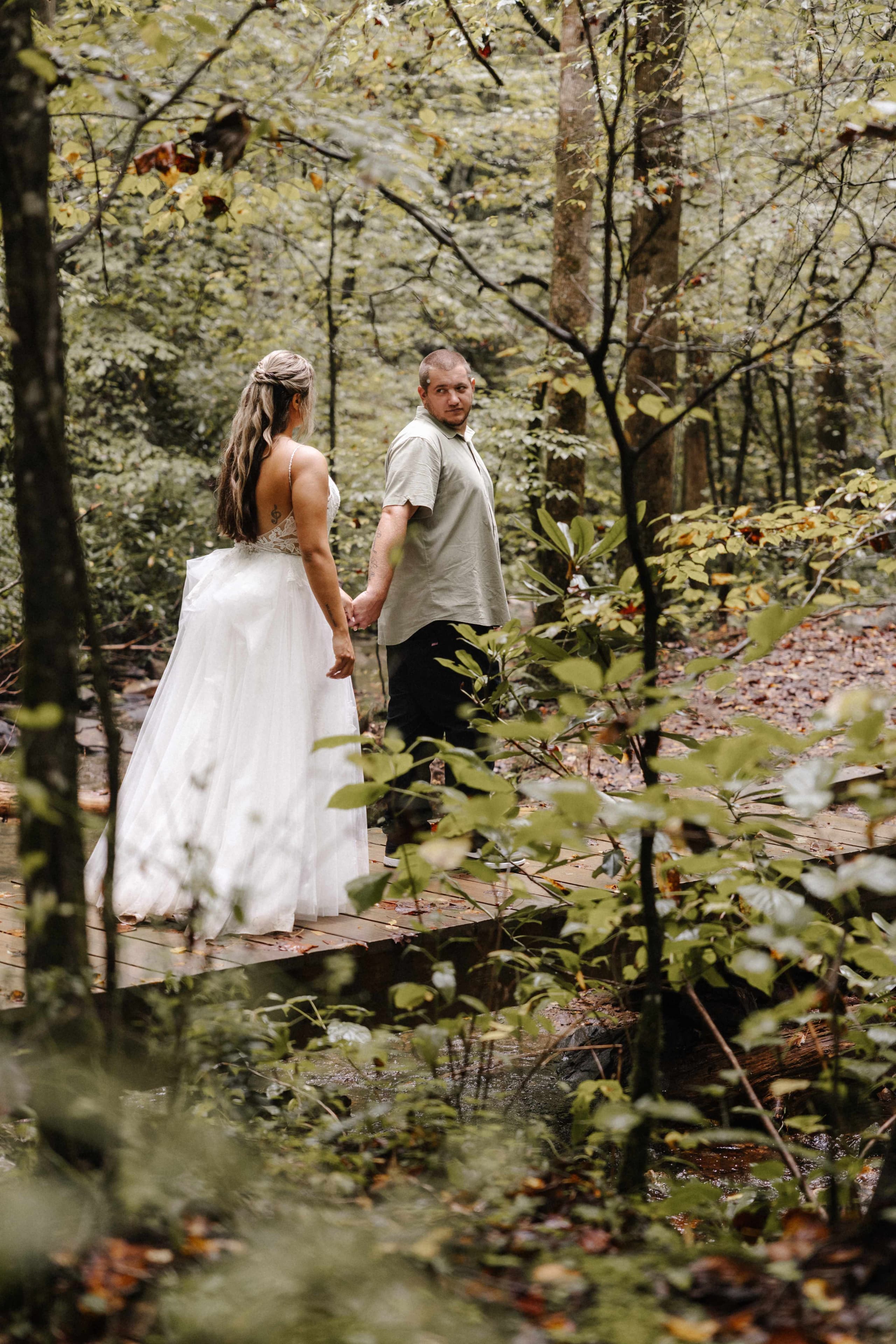 Couple walking on wooden bridge in lush green forest