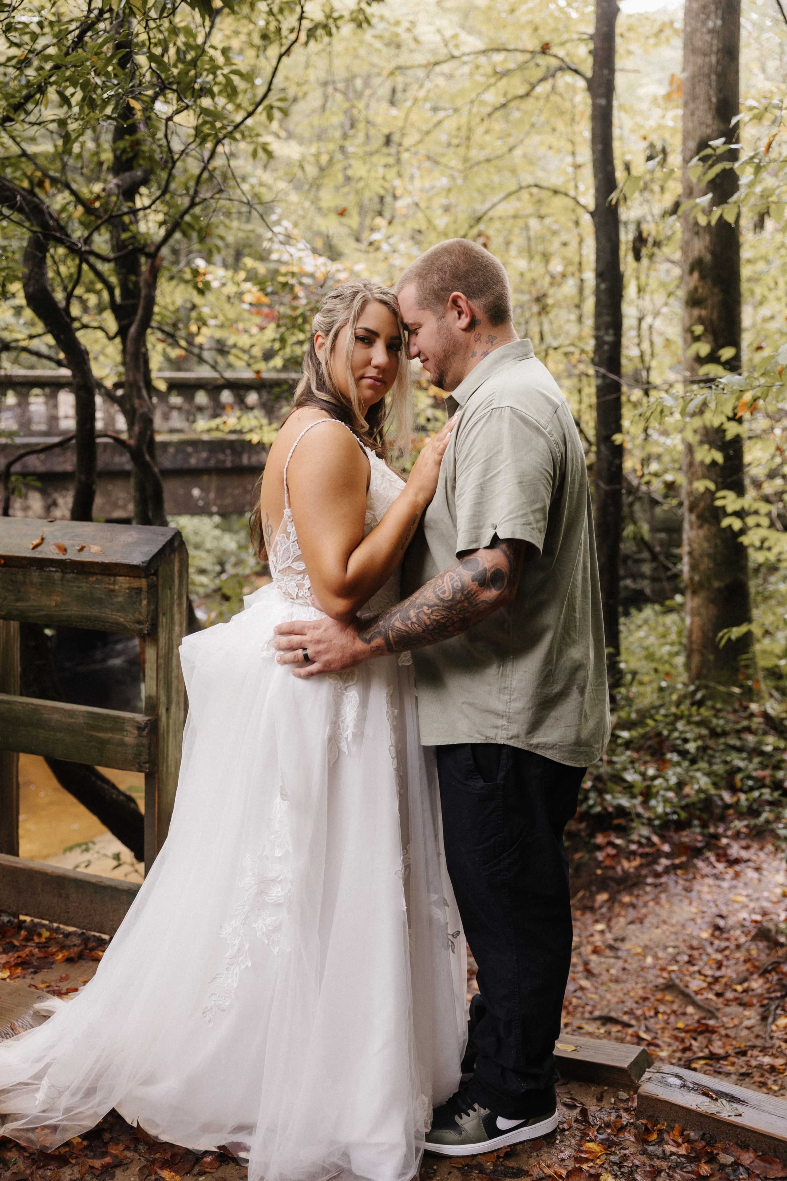 Intimate couple portrait on bridge showing groom's tattoos
