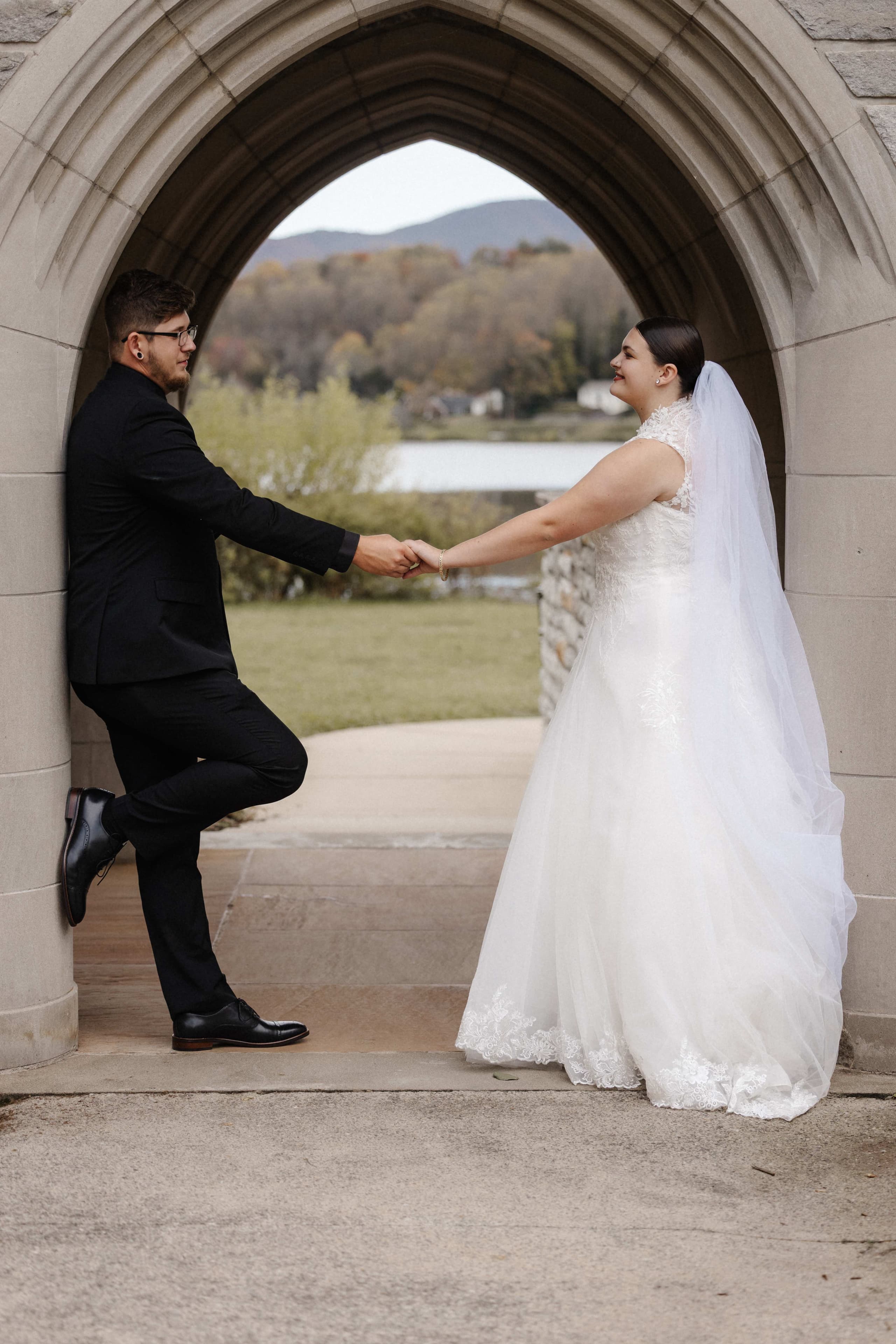 Couple in gothic stone archway with mountain lake view behind