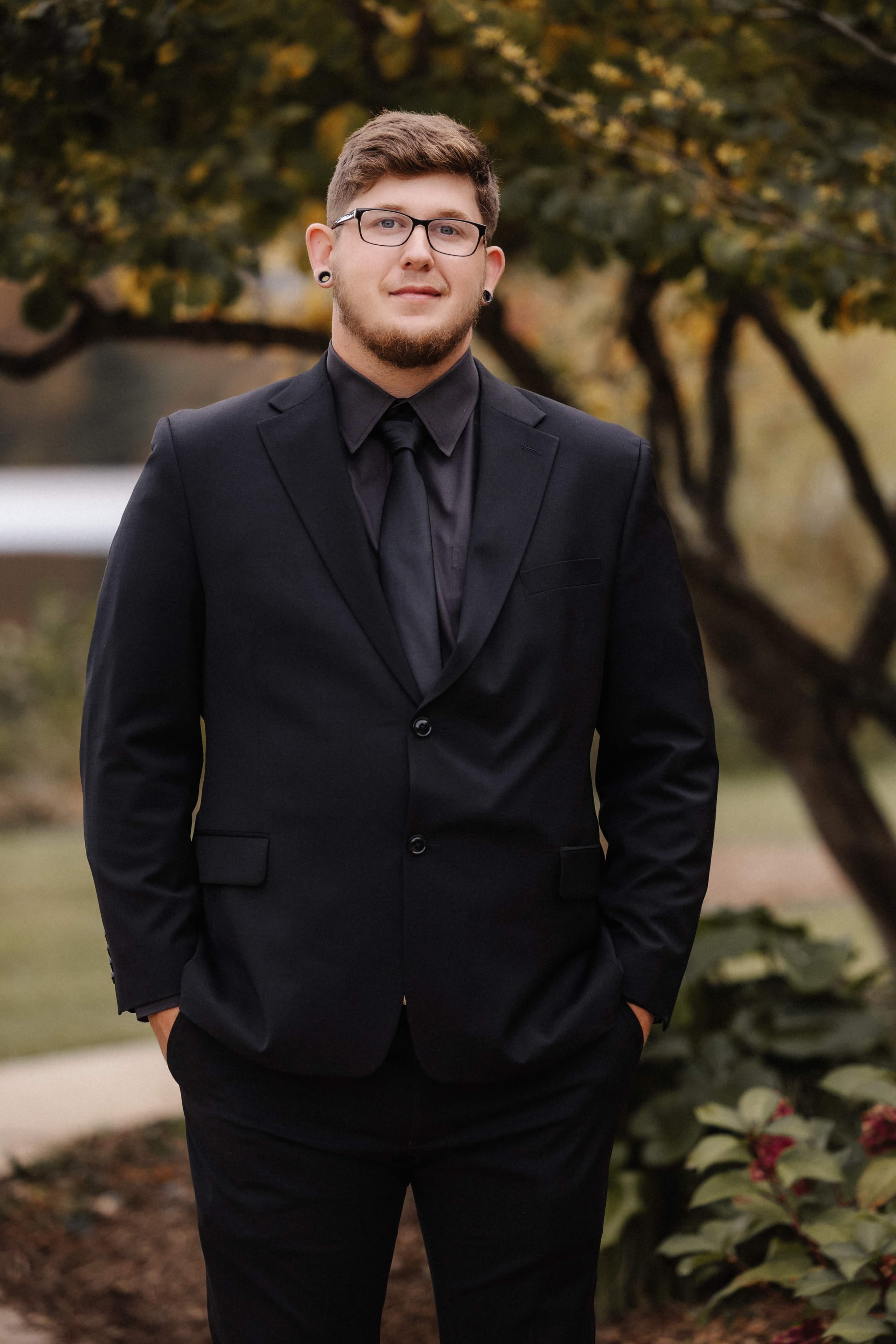 Groom portrait in all black suit with hands in pockets