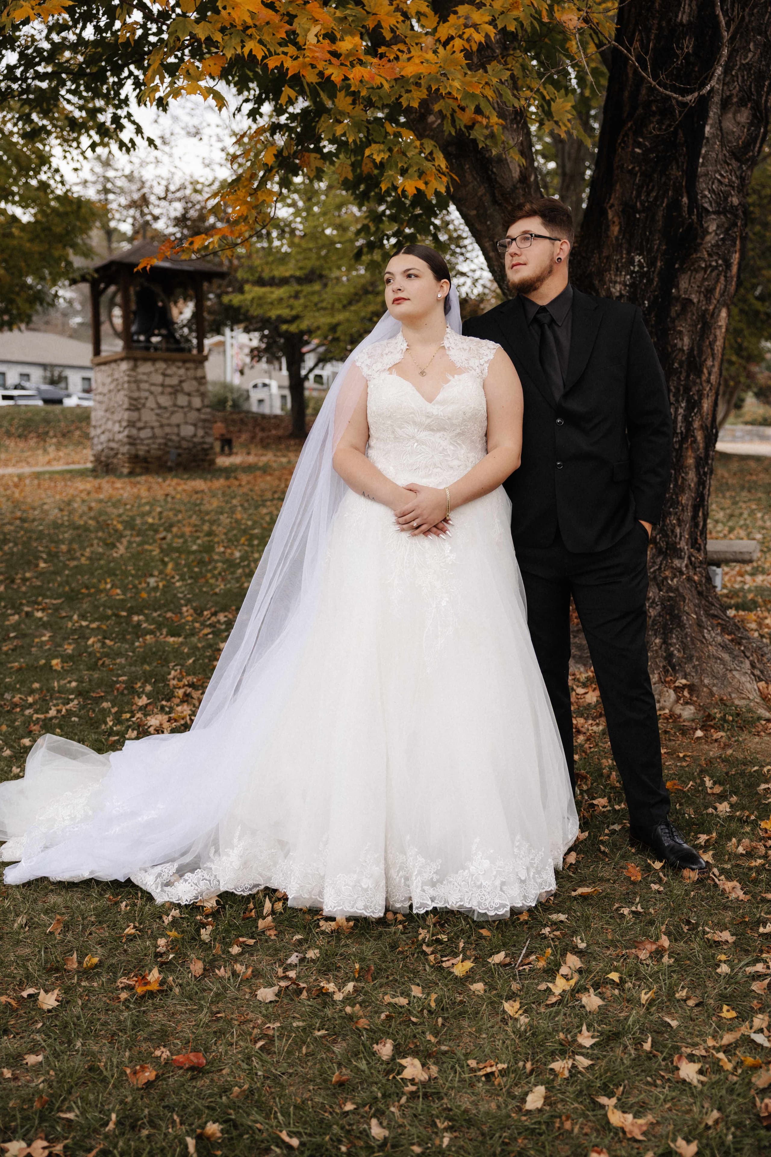 Full length couple portrait under fall tree with cathedral veil