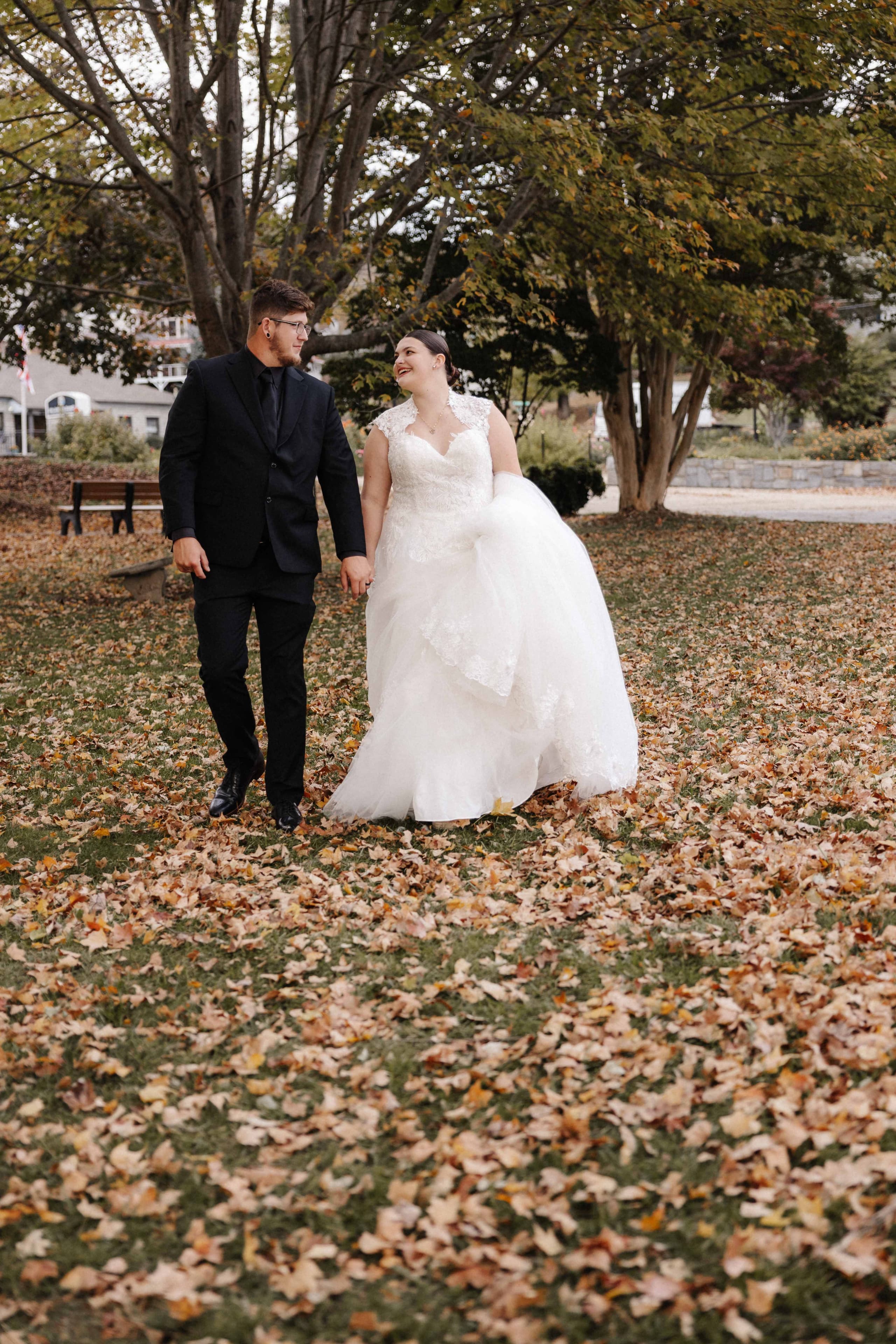 Couple walking through fall leaves in park with colorful foliage