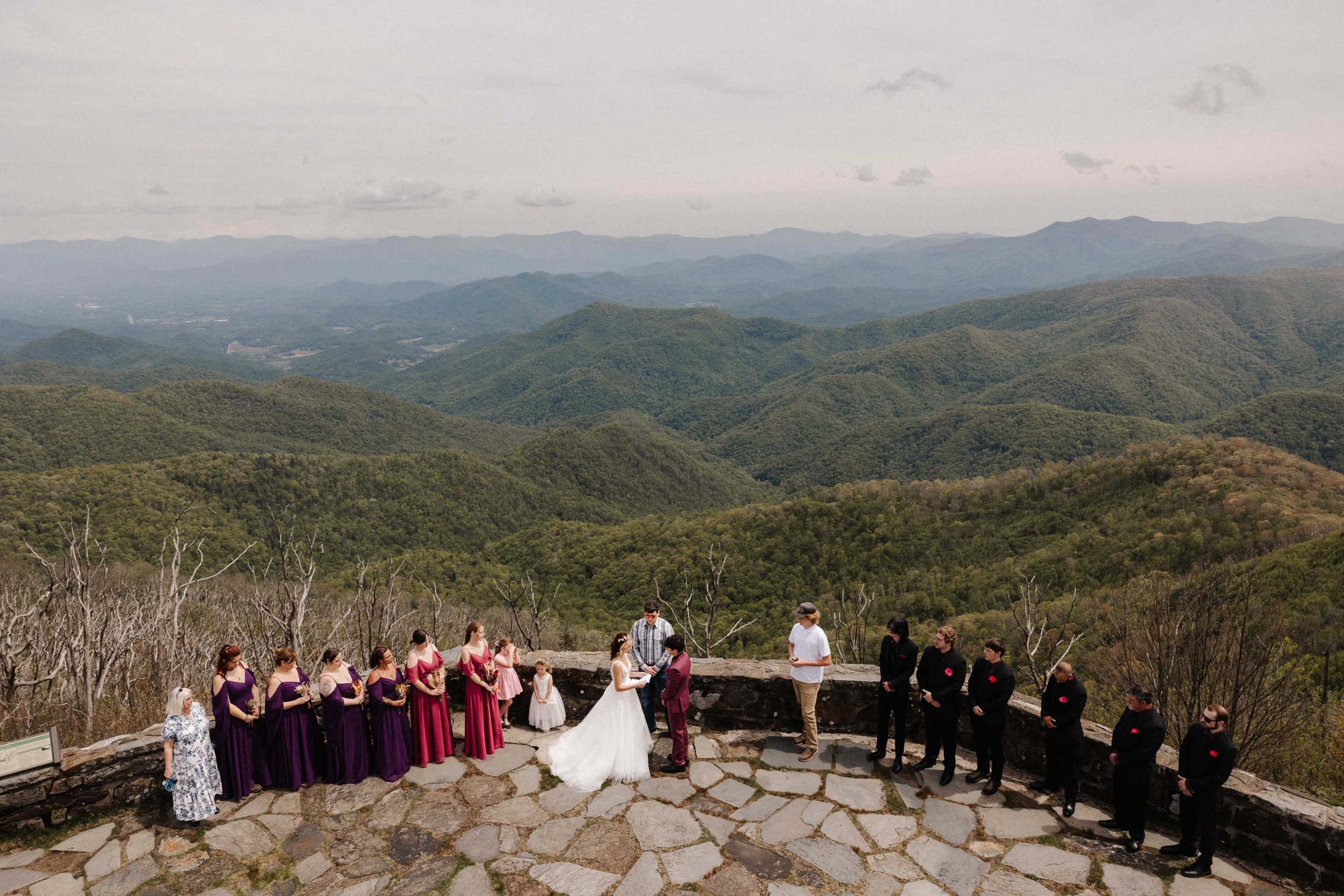 Wide shot of ceremony at mountain overlook with wedding party