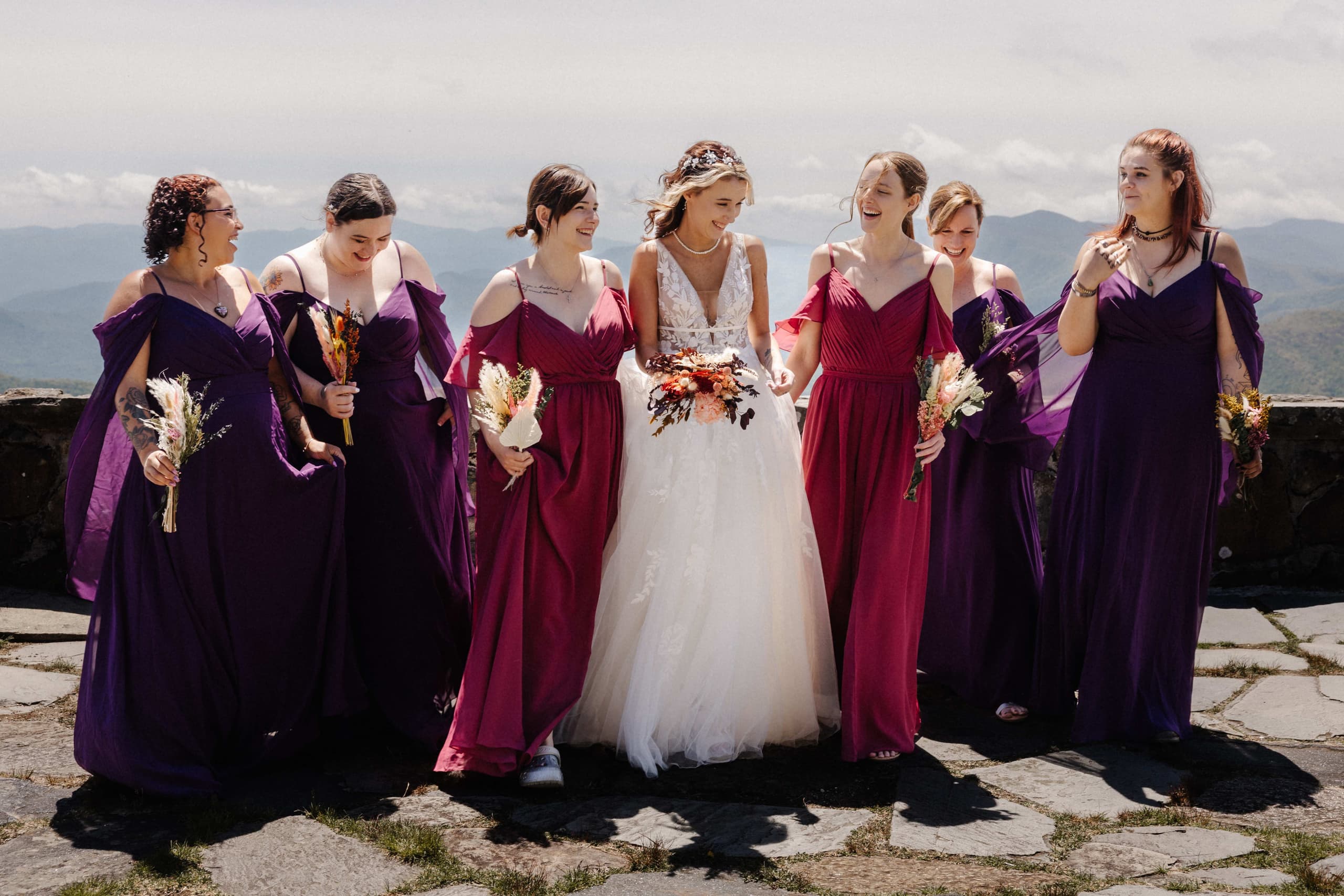 Bride with bridesmaids walking and laughing together on mountain