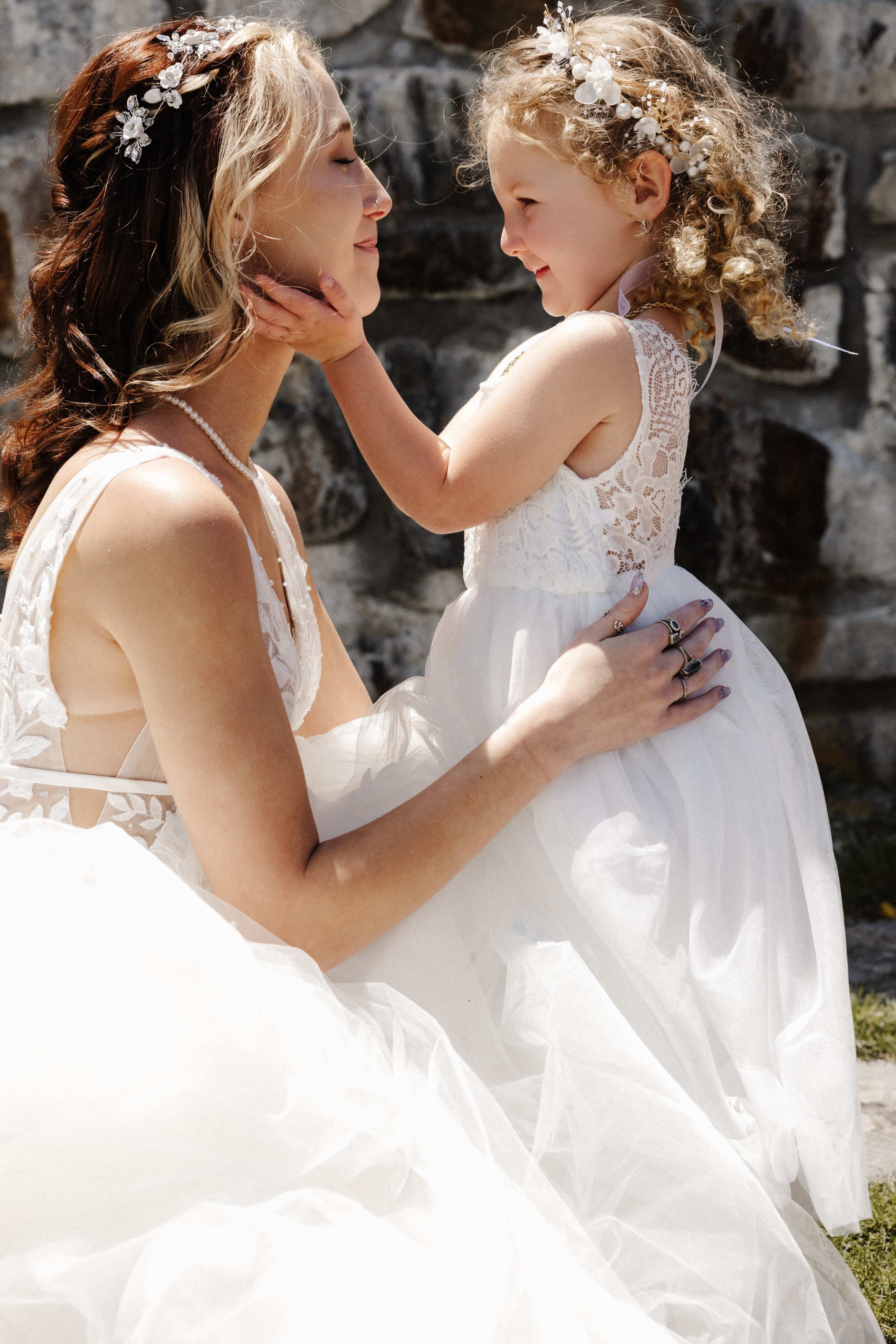 Sweet moment between bride and flower girl touching faces