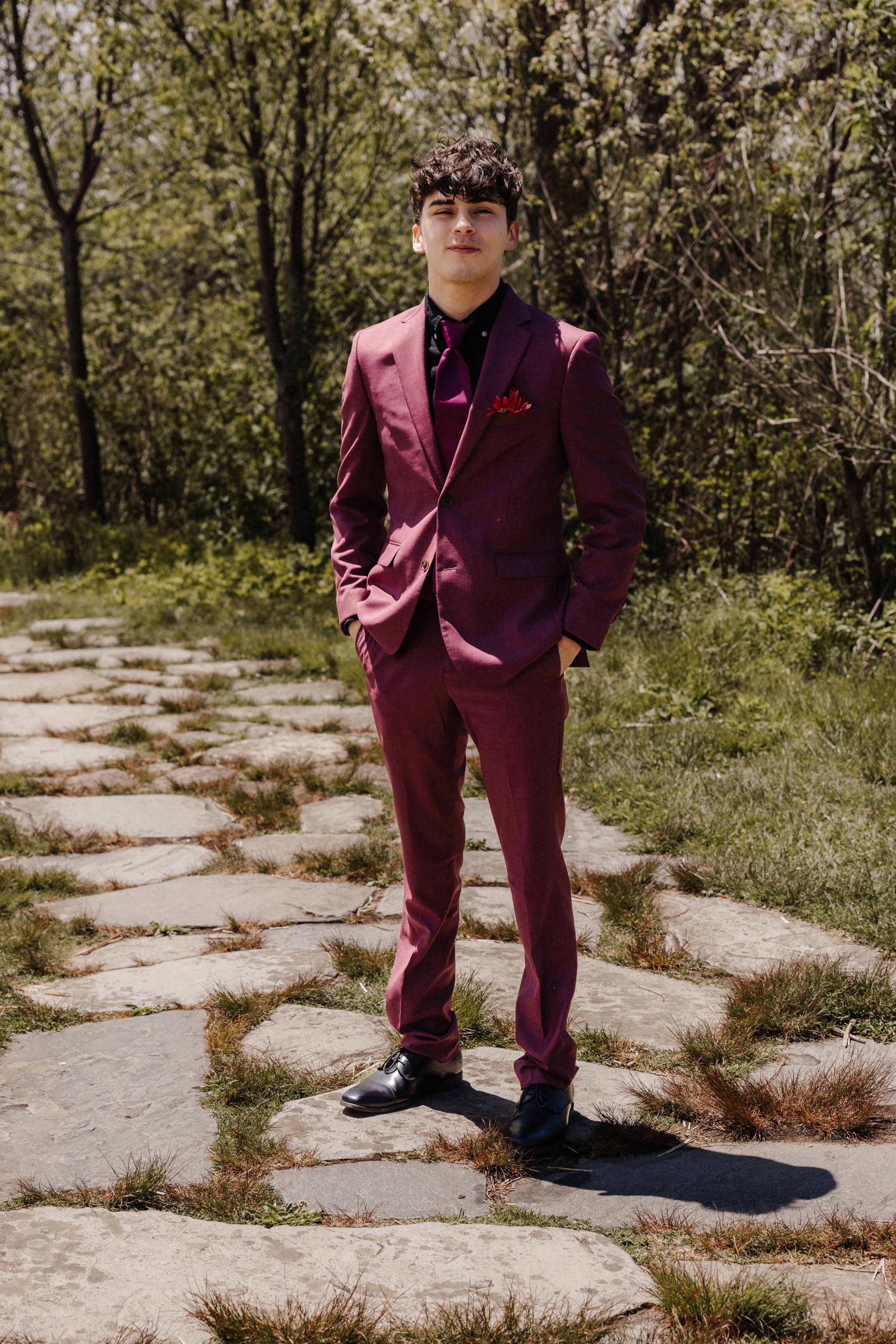 Groom solo full length portrait in burgundy suit on stone path