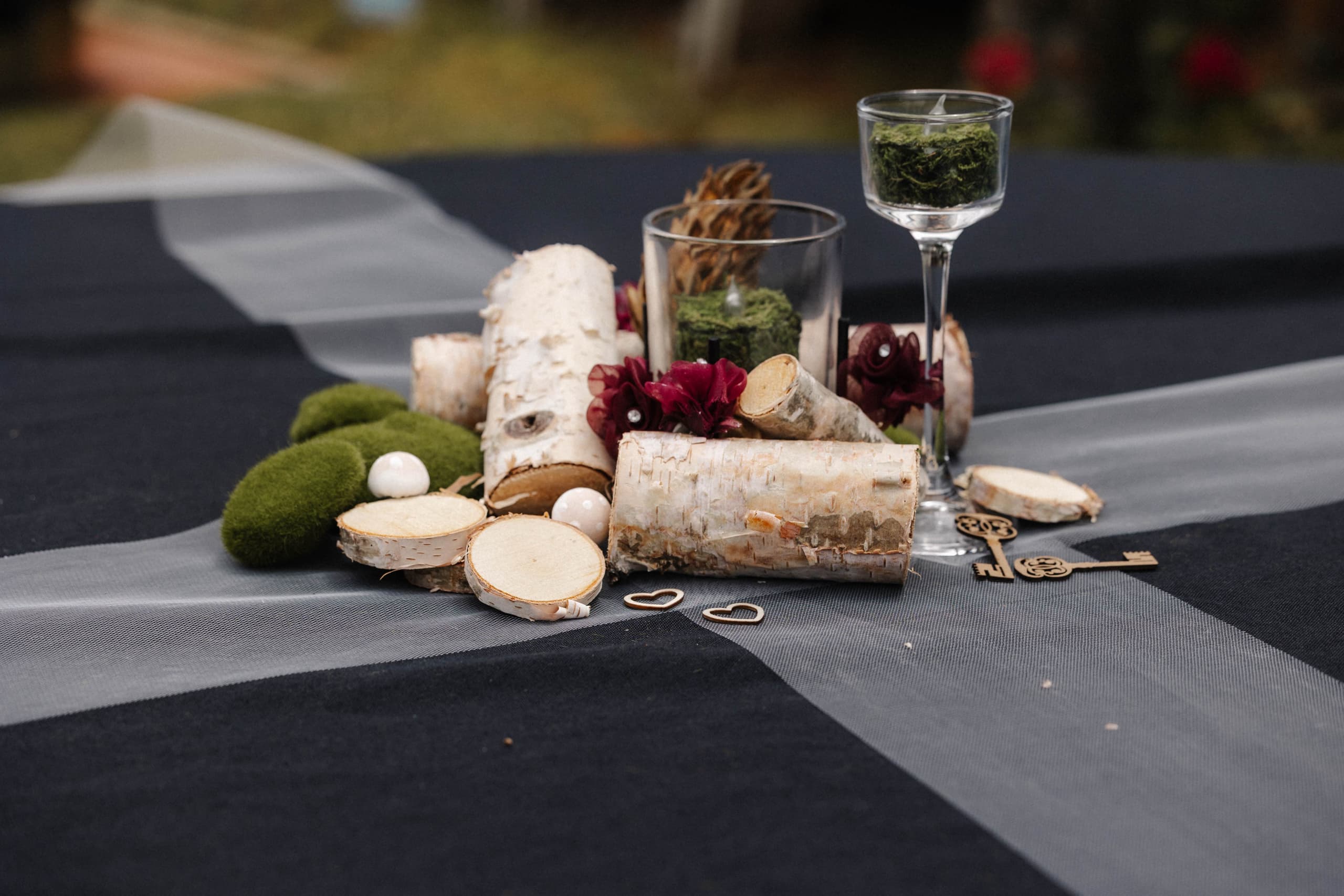 Rustic birch log centerpiece with moss and burgundy flowers