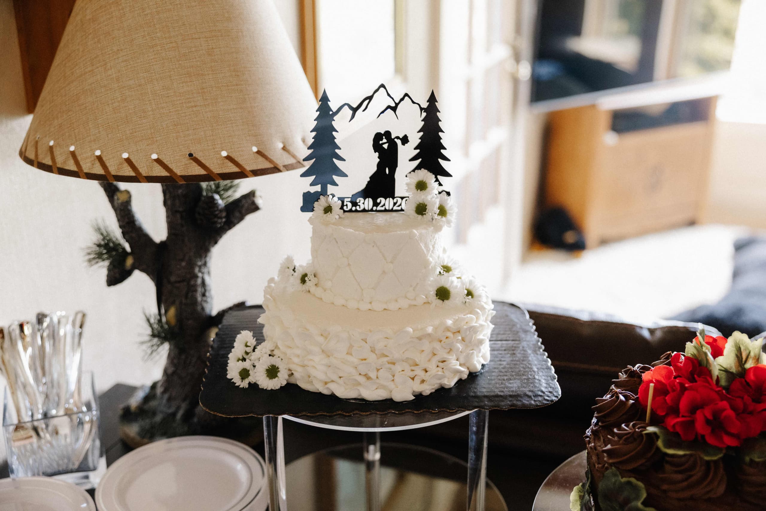 Three-tier white wedding cake with mountain silhouette topper