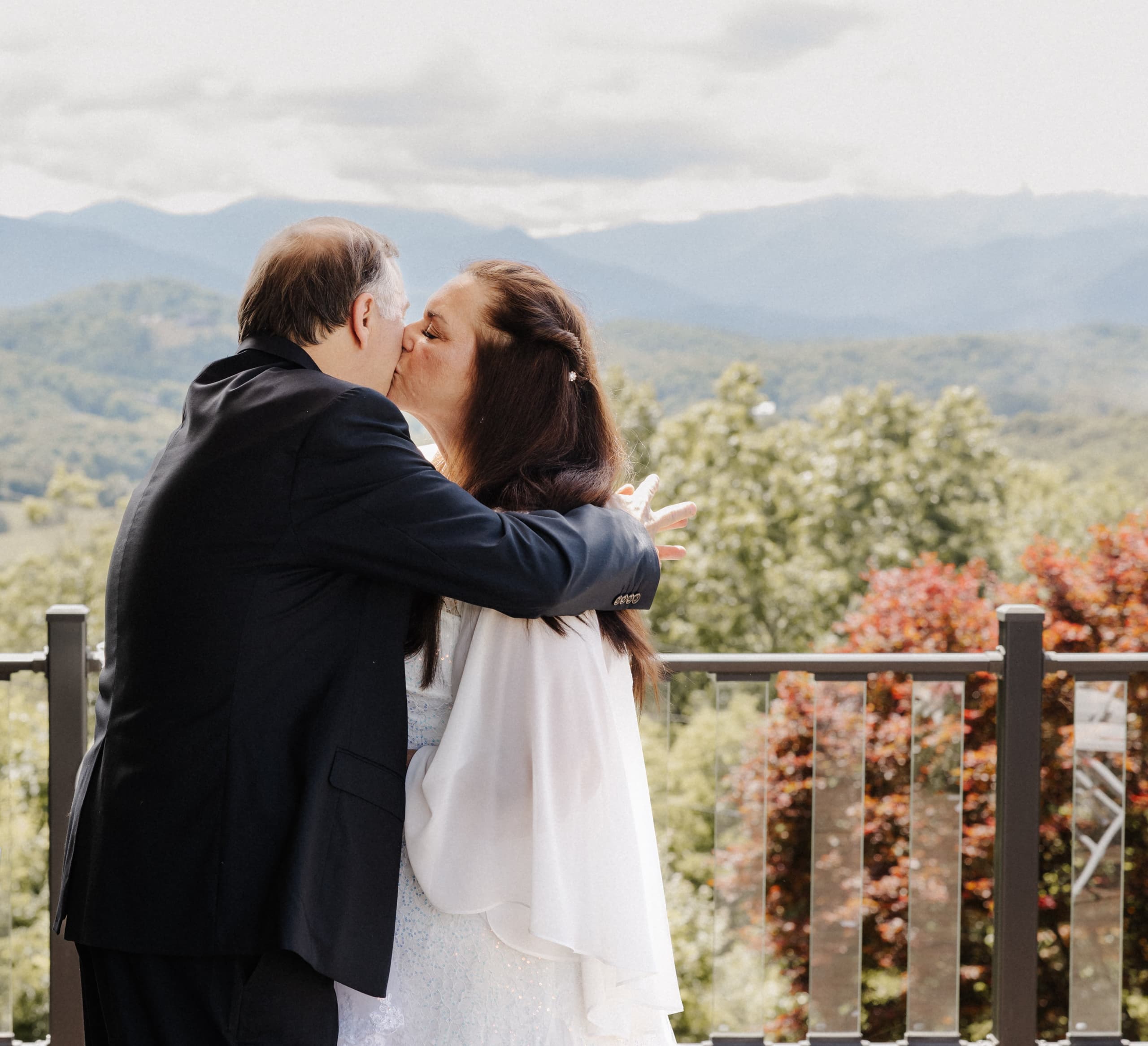 Couple kissing on deck with mountain views and fall foliage