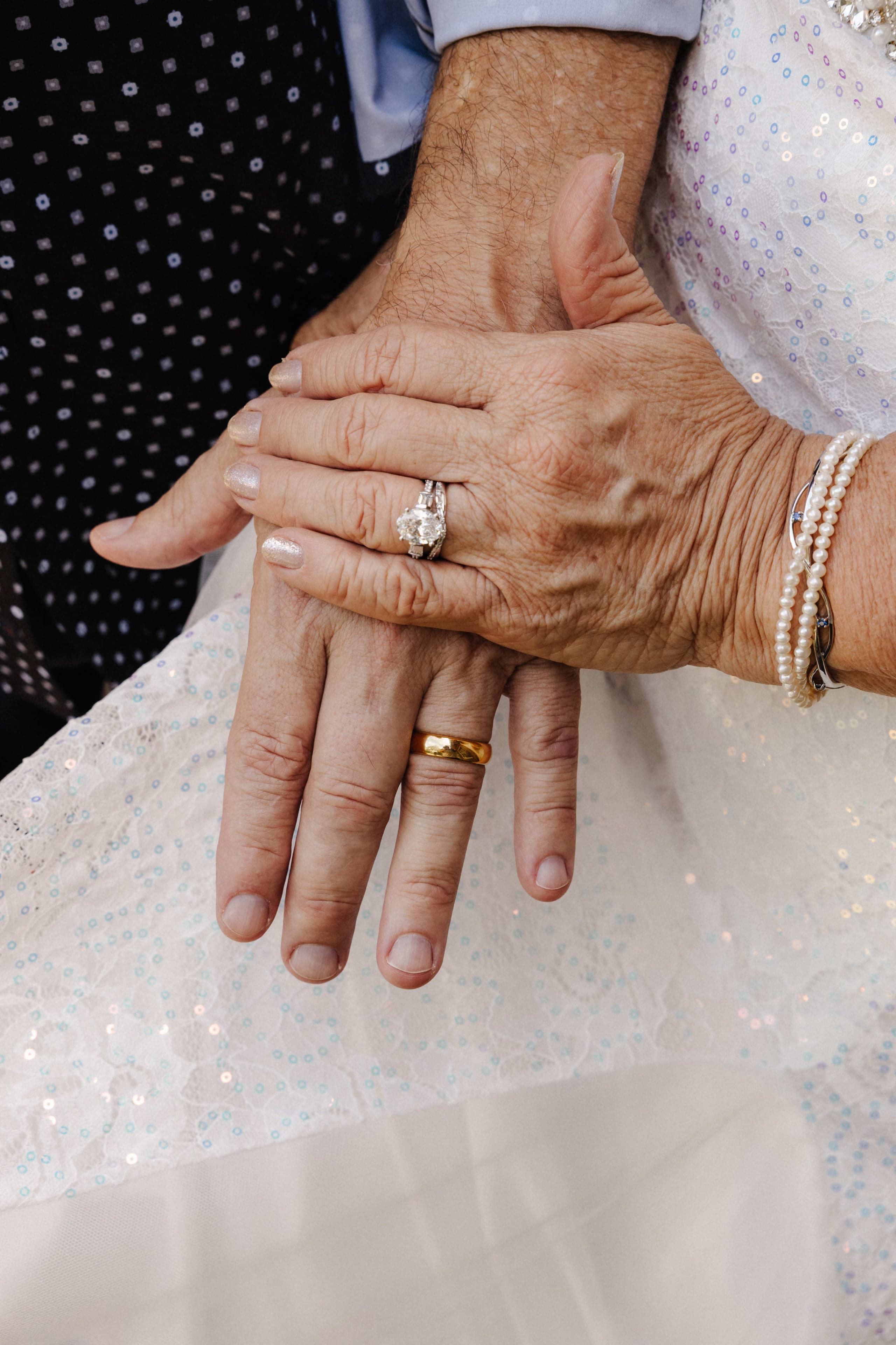 Close-up of couple hands with wedding rings and pearl bracelet