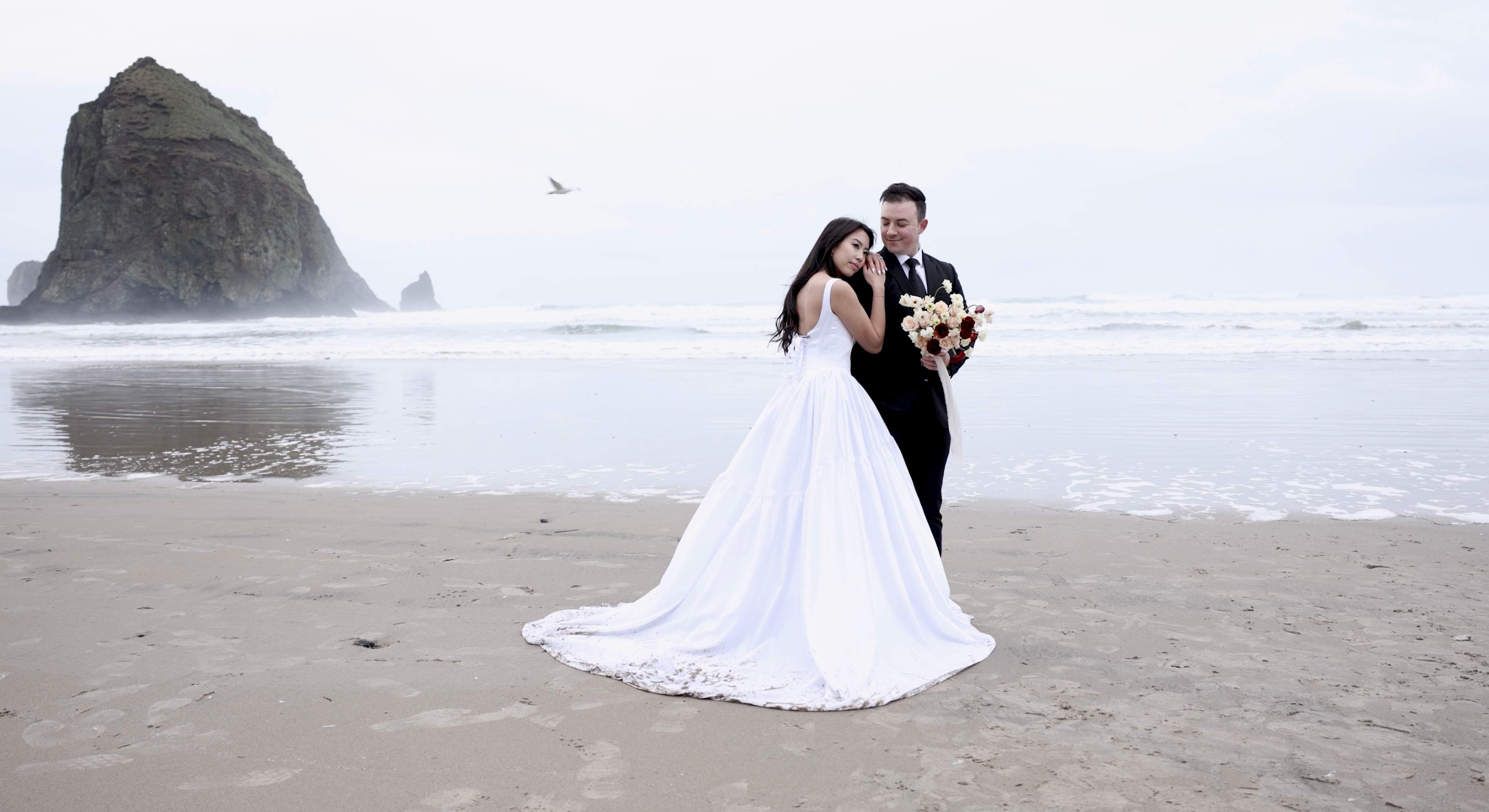 Couple embracing on beach with sea stack