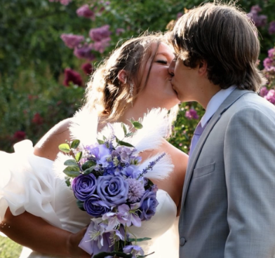 Couple kissing with purple bouquet in garden