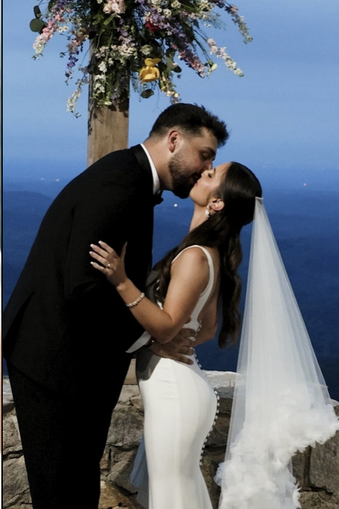 Couple kissing under floral arch with ocean view